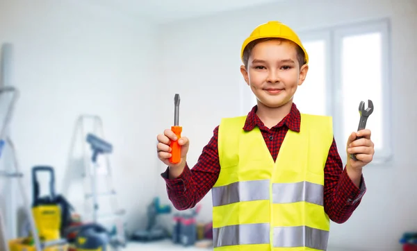 Мальчик в строительном шлеме с отверткой и гаечным ключом — стоковое фото