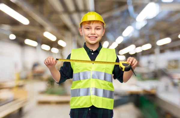 Niño en casco de construcción y chaleco con regla — Foto de Stock