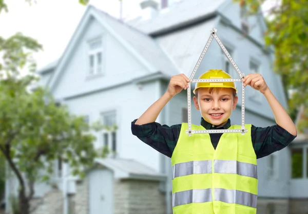 Niño en casco con regla en forma de casa — Foto de Stock