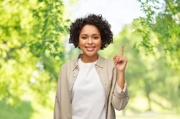 Woman pointing finger up over natural background — Stock Photo, Image