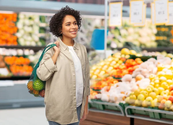 Mulher sorridente com alimentos em saco de corda reutilizável — Fotografia de Stock