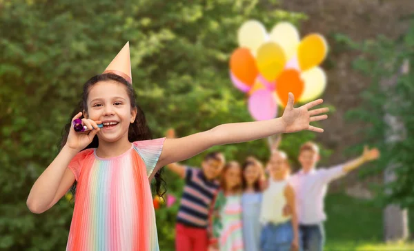 Glückliches Mädchen mit Gebläse auf Geburtstagsparty im Park — Stockfoto