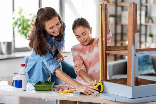 Madre e hija con regla midiendo mesa vieja —  Fotos de Stock