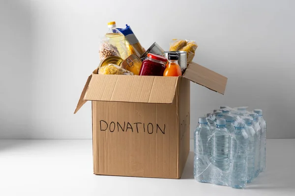 Närbild av livsmedel i donationslåda och vatten — Stockfoto
