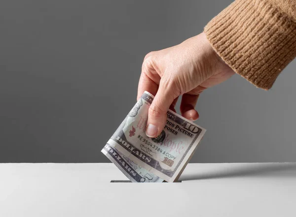Close up of hand putting money into donation box — Stock Photo, Image