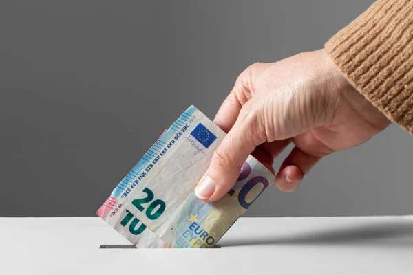 Close up of hand putting money into donation box — Stock Photo, Image