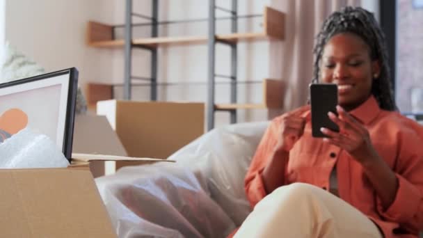 Счастливая женщина со смартфоном переезжает в новый дом — стоковое видео