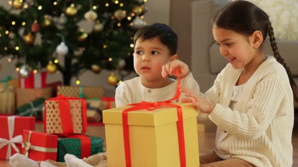 Glada barn öppnar julklappar hemma — Stockvideo