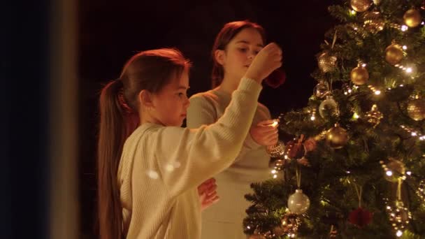 Glada flickor dekorera julgran hemma — Stockvideo