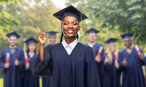 Šťastná studentka-absolventka, ukazující prstem nahoru — Stock fotografie