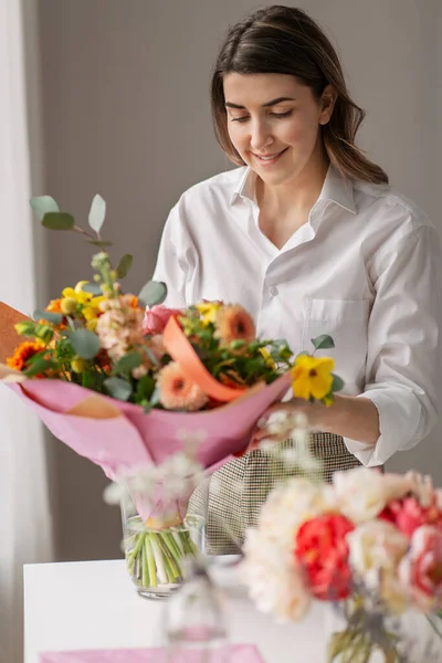 Mulher feliz organizando flores em vaso em casa — Fotografia de Stock