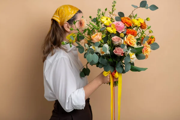 Vrouw holding bos van bloemen op beige achtergrond — Stockfoto