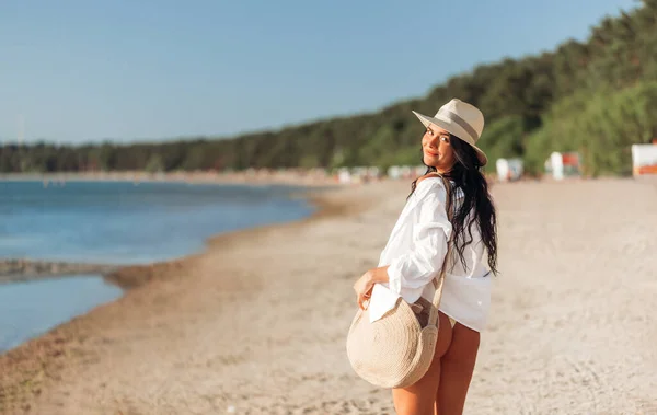 Szczęśliwa kobieta z torbą spacerując po letniej plaży — Zdjęcie stockowe