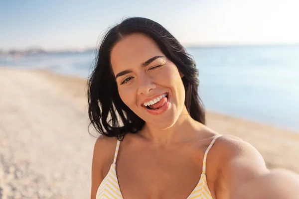 Donna sorridente in bikini scattare selfie sulla spiaggia — Foto Stock