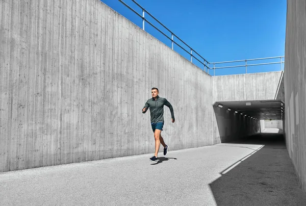 Young man running out of tunnel — Stock Photo, Image