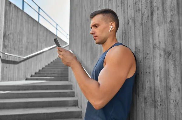 Jeune athlète homme avec écouteurs et smartphone — Photo