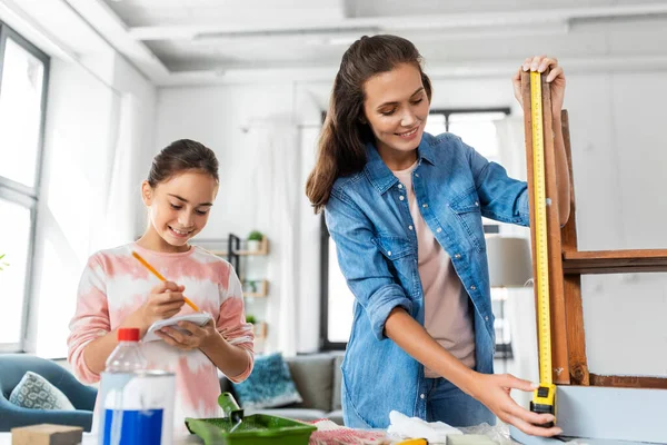Mother and daughter with ruler measuring old table — Stock Photo, Image