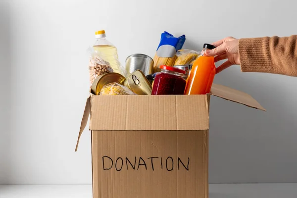 Close-up van voedsel in donatiedoos en hand — Stockfoto