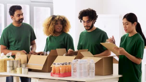 Voluntários felizes embalando alimentos em caixas de doação — Vídeo de Stock