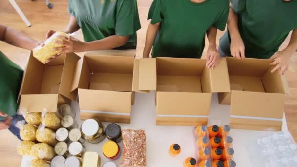 Gelukkige vrijwilligers die voedsel in donatiedozen verpakken — Stockvideo