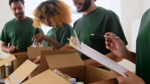 Szczęśliwi wolontariusze pakujący żywność w pudełka darowizn — Wideo stockowe