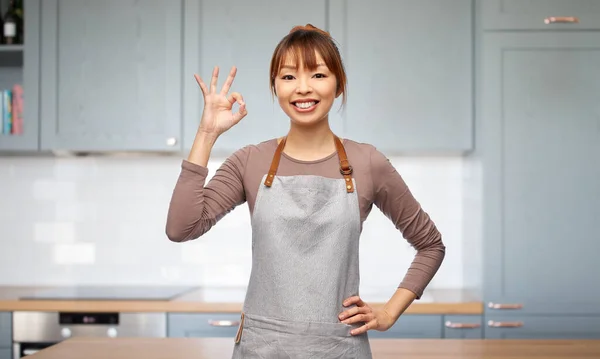 Boldog nő kötényben mutatja rendben gesztus a konyhában — Stock Fotó