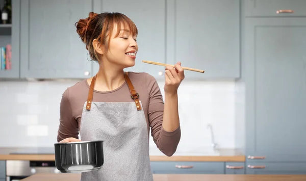 Щаслива жінка в фартусі з каструлею на кухні — стокове фото