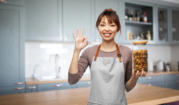 Mujer en delantal con pasta en tarro mostrando signo ok —  Fotos de Stock
