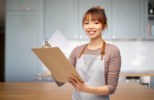 Female chef or waitress in apron with clipboard — Stock Photo, Image