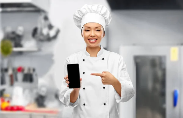 Chef mujer sonriente con teléfono inteligente en la cocina — Foto de Stock