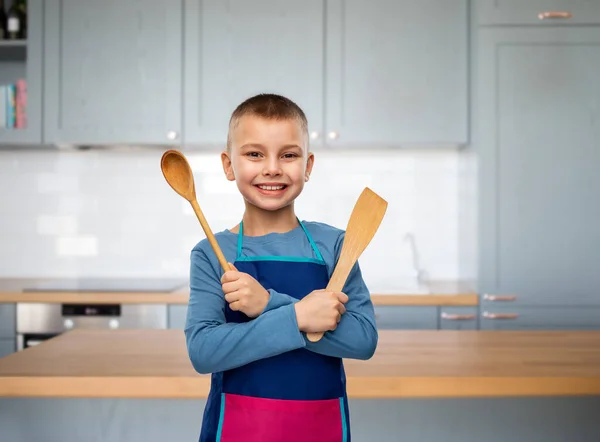 快乐的小男孩，穿着围裙，拿着勺子和铲子 — 图库照片