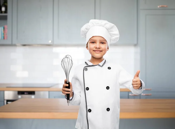 Menina em chefs toque com whisk mostrando polegares para cima — Fotografia de Stock