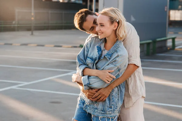Feliz jovem casal abraçando no estacionamento da cidade — Fotografia de Stock