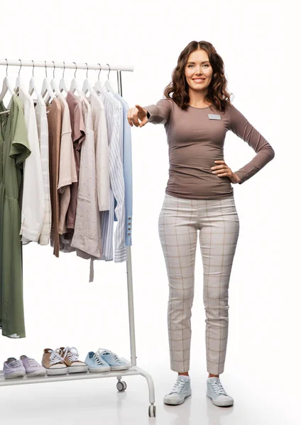 Asistente de tienda femenina feliz con ropa en percha —  Fotos de Stock