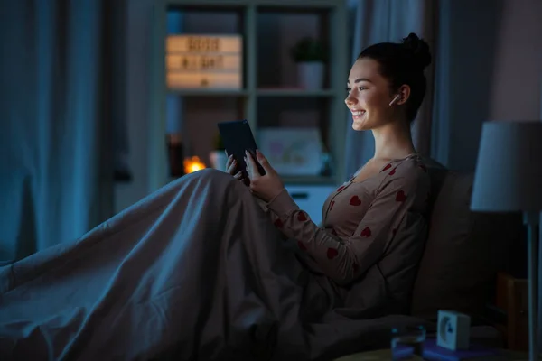 Tiener meisje met tablet pc en oortjes in bed — Stockfoto