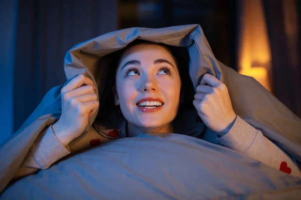 Glückliches Teenager-Mädchen liegt unter Decke im Bett — Stockfoto