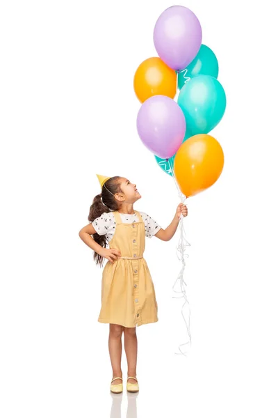 Menina feliz em chapéu de festa de aniversário com balões — Fotografia de Stock