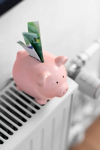 Banco porquinho com dinheiro no radiador em casa — Fotografia de Stock