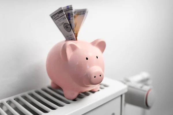 Banco porquinho com dinheiro no radiador em casa — Fotografia de Stock