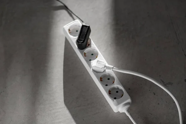 Close up of socket with plugs and charger on floor — Stock Photo, Image