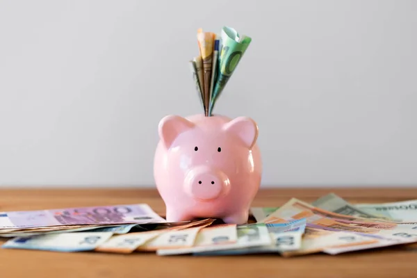 Close up of piggy bank with money on wooden table — Stock Photo, Image