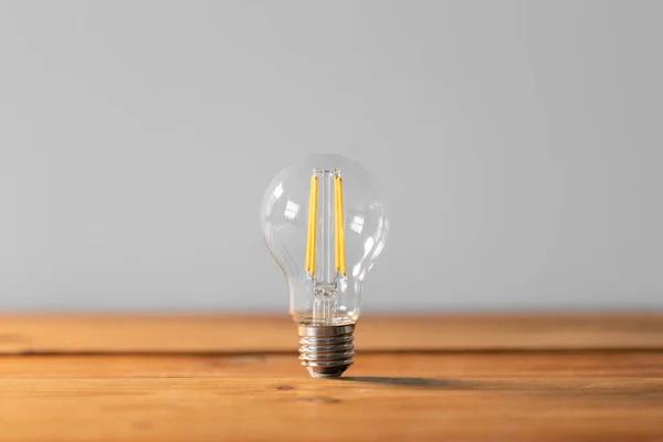 Close up of lightbulb on wooden table — Stock Photo, Image