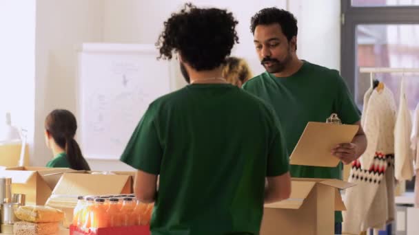 Skupina dobrovolníků balí jídlo do dárcovských krabic — Stock video