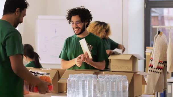 Группа волонтеров упаковывает еду в коробки для пожертвований — стоковое видео