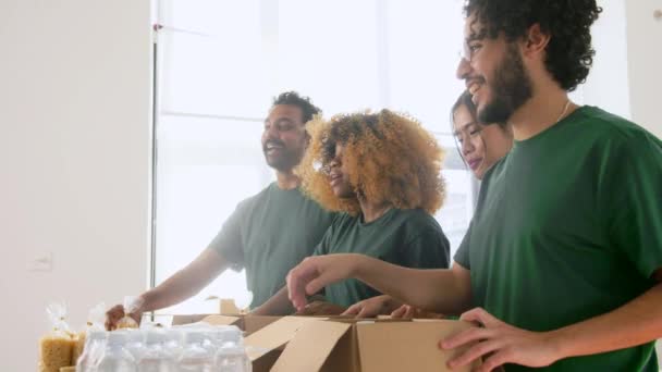 Voluntarios felices empacando comida en cajas de donaciones — Vídeo de stock