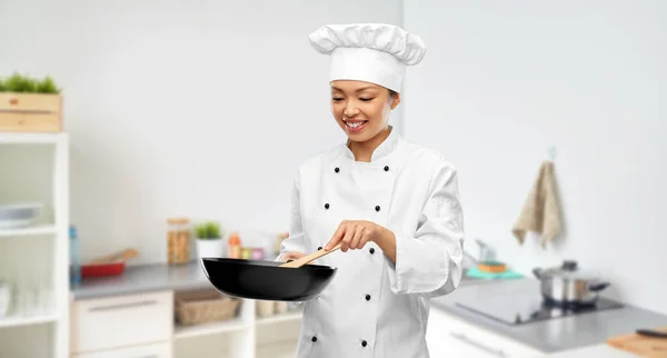 Sorrindo chef fêmea cozinhar alimentos na frigideira — Fotografia de Stock