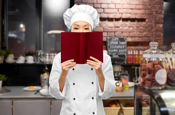Köchin versteckt sich hinter Kochbuch — Stockfoto