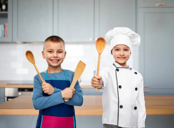 Niños felices con cuchara y espátula en la cocina —  Fotos de Stock
