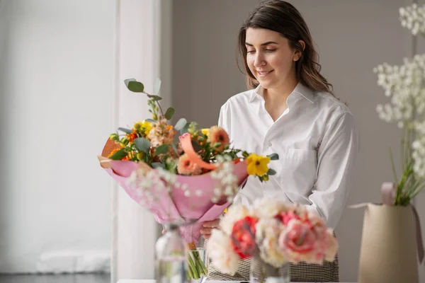 Mulher feliz organizando flores em vaso em casa — Fotografia de Stock