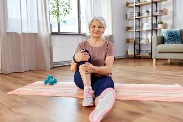Usmívající se starší žena cvičení na podložce doma — Stock fotografie